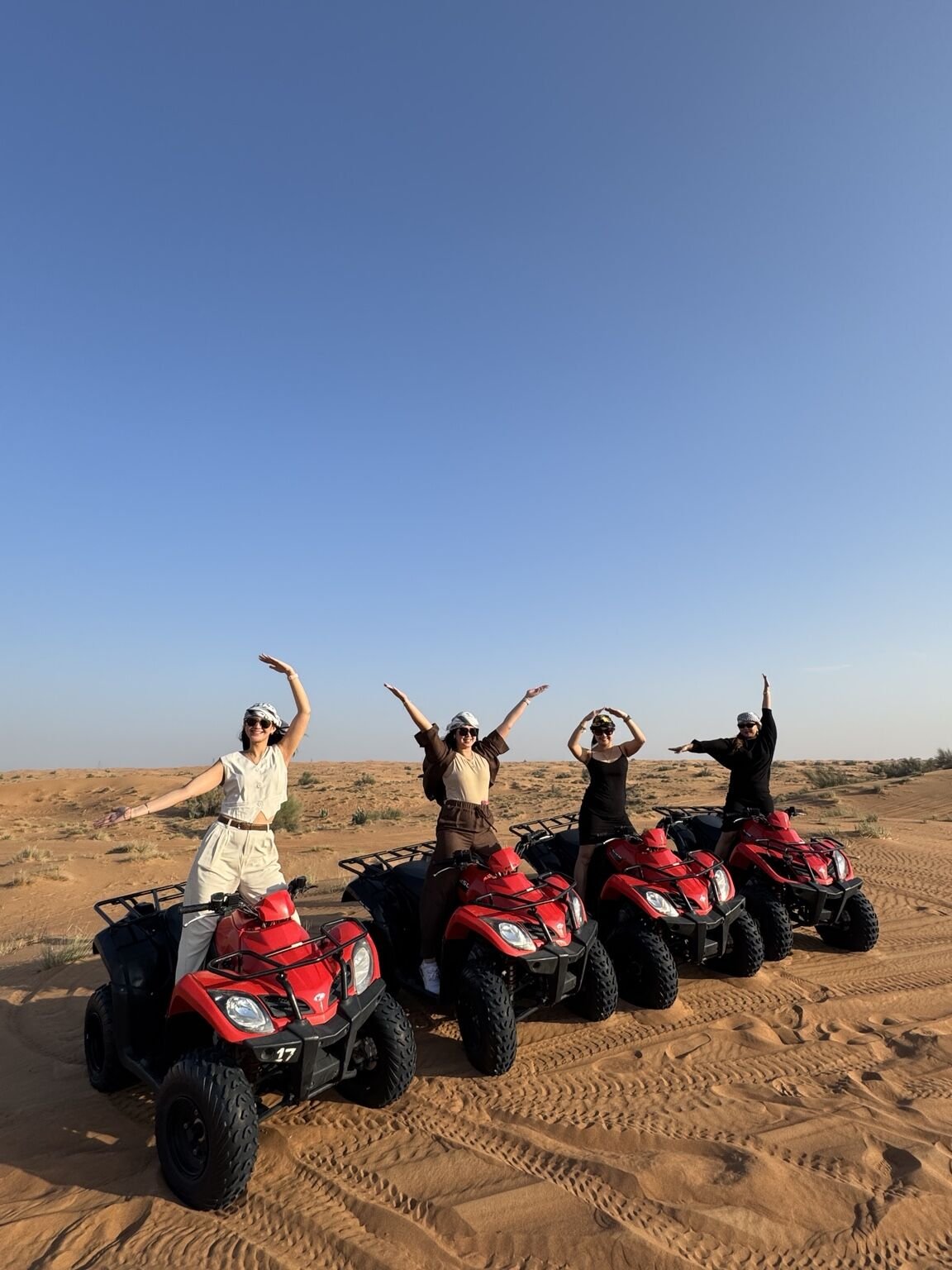 Group of guests enjoying red quad bikes in the Dubai desert